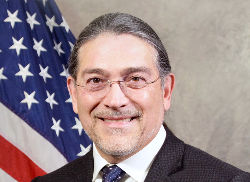 Official photograph of US Census Bureau director Robert Santos, with US flag in background.