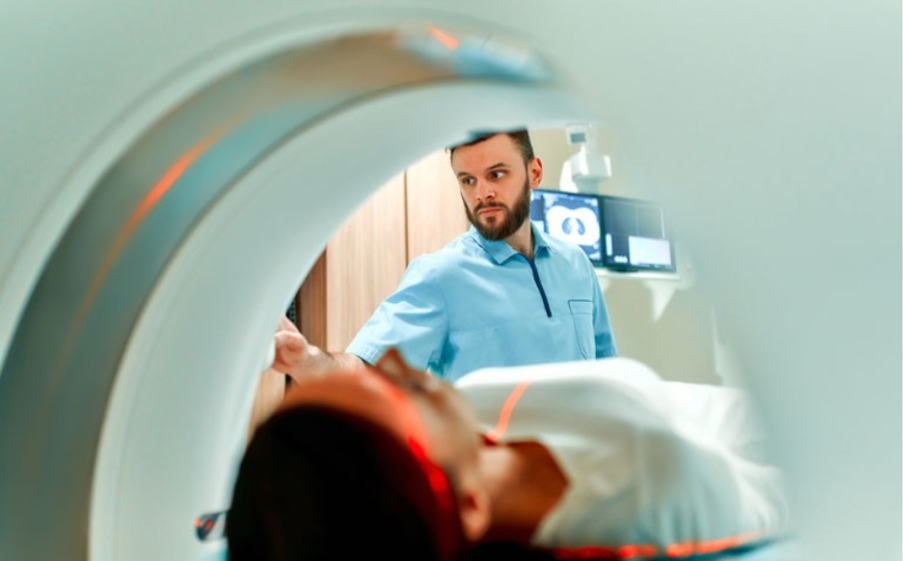 A radiographer supervises a patient entering a CT scanner.