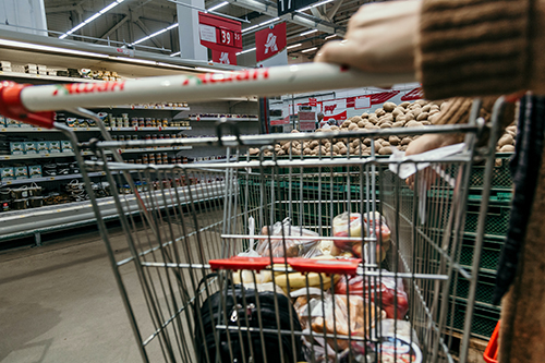 A shopping trolley being pushed around a supermarket. Photo by Marjan Blan | @marjanblan on Unsplash.