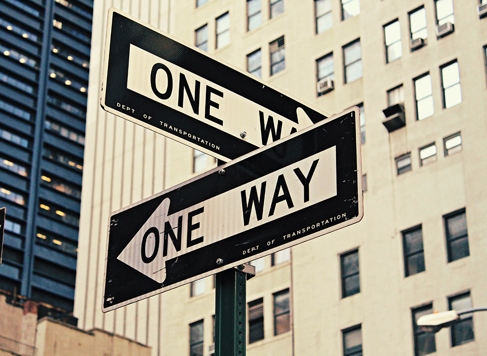New York road signs pointing left and right, both reading &#039;One Way'.