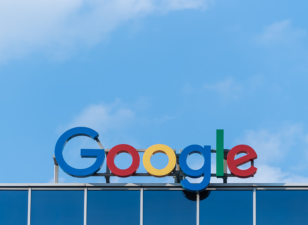 Google logo on top of building, against a blue sky.